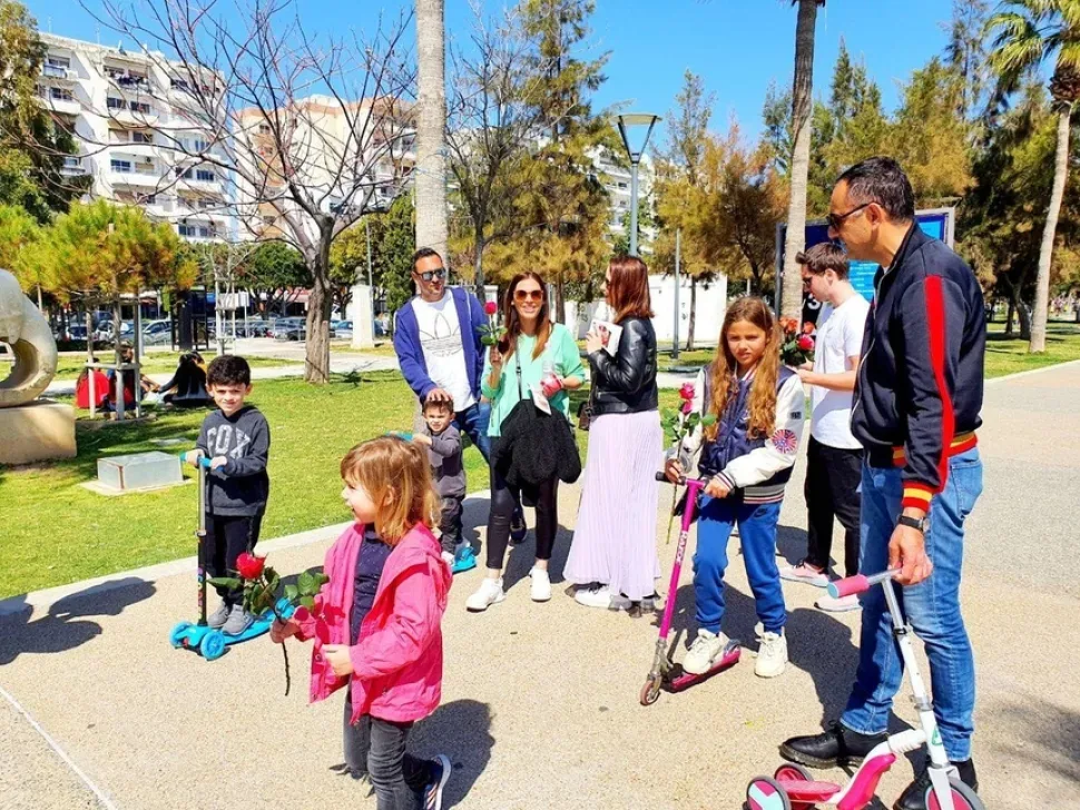 Женщина с маленьким ребёнком позирует у баннера Cyprus Butterfly и розы