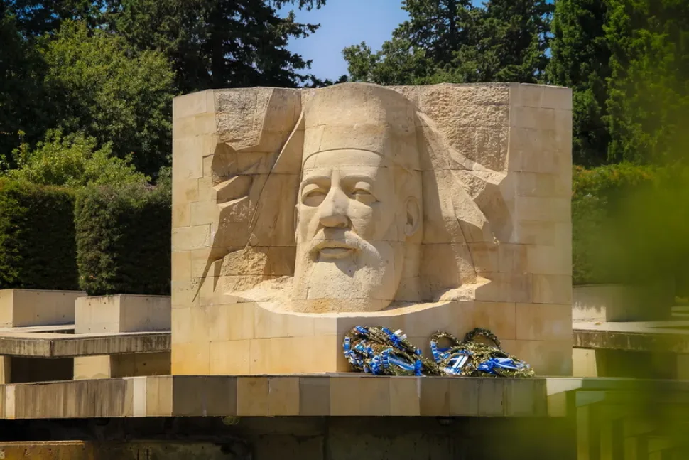 Фасадная часть памятника Макариосу III среди кипарисов и зелёных насаждений
