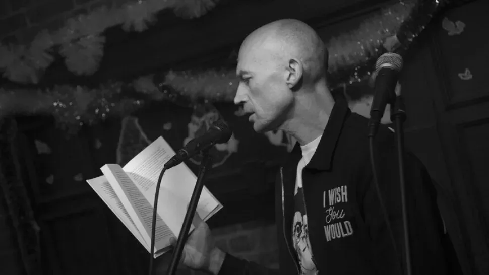 Писатель читает текст в микрофон на сцене во время выступления