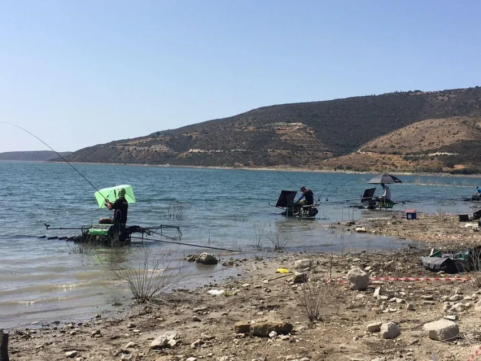 Рыболов регулирует снасти у воды на дамбе во время состязаний