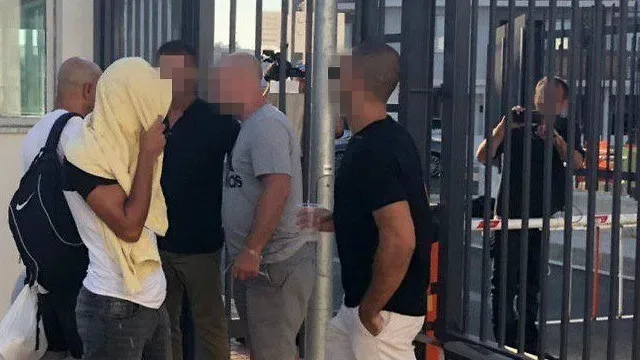 Группа молодых мужчин с размытыми лицами у ограждения возле входа