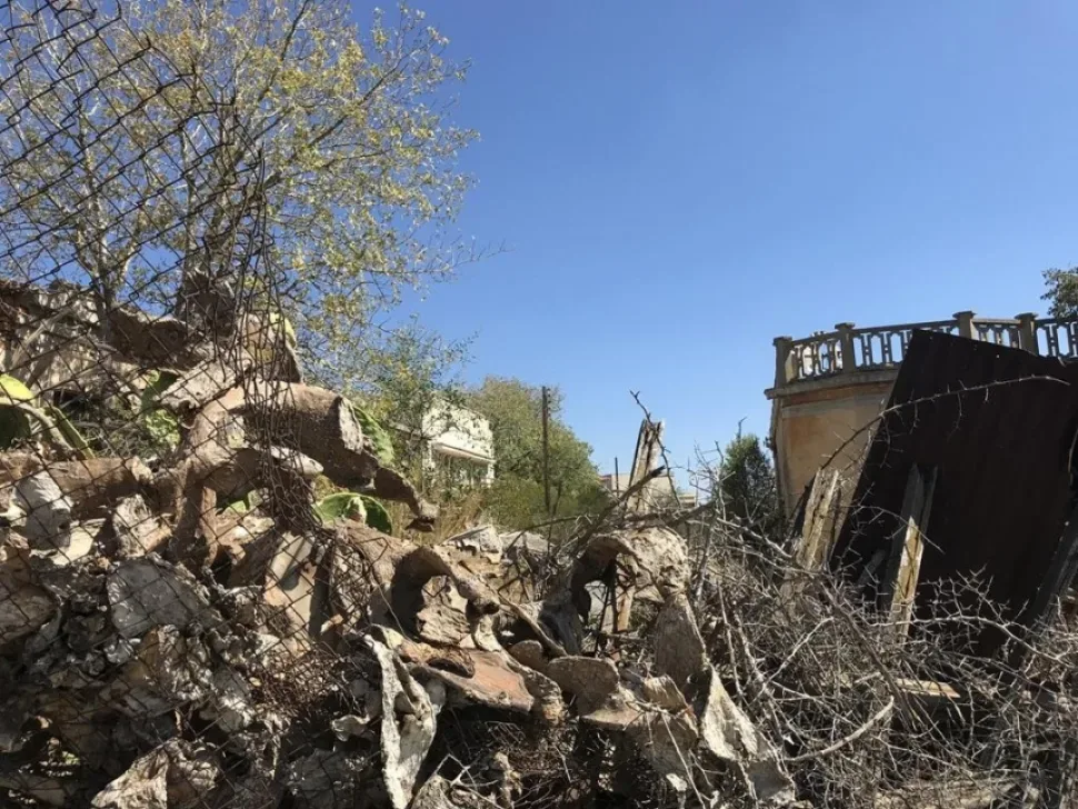 Разрушенная ограда и завалы строительного мусора на пустыре города