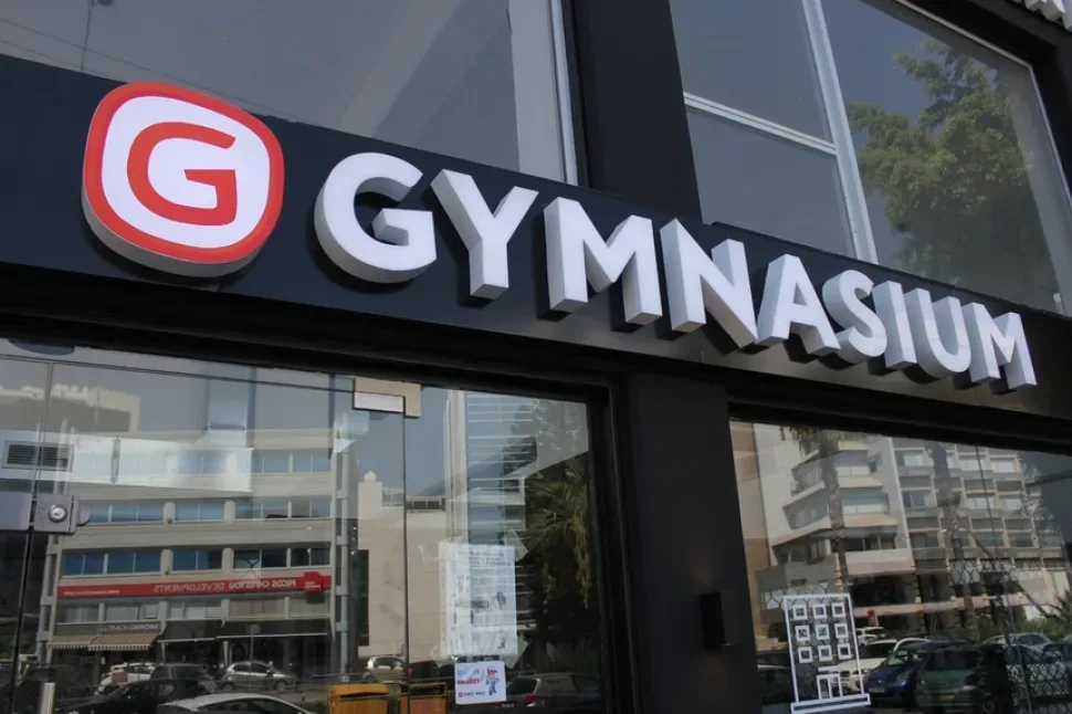 Входная вывеска спортзала Gymnasium на черном фасаде здания Входная вывеска спортзала Gymnasium на черном фасаде здания