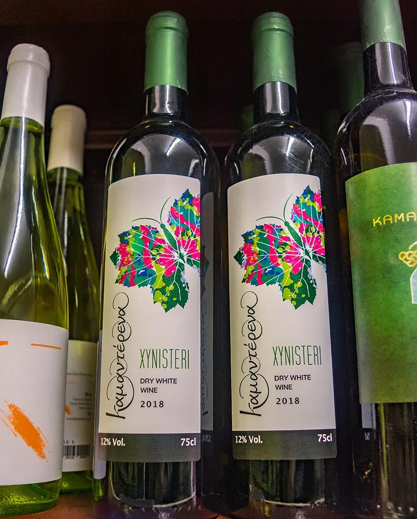 Две бутылки Xynisteri с ярким цветочным рисунком на этикетке рядом друг с другом