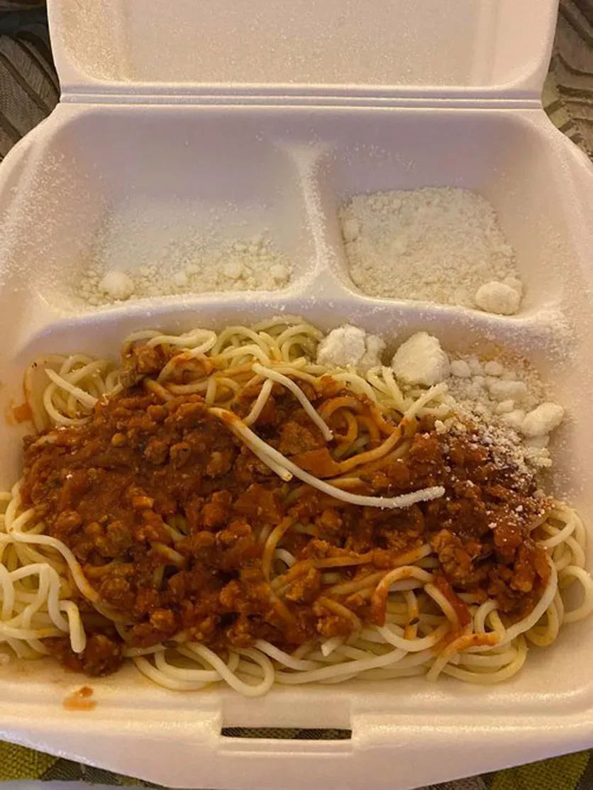 Контейнер с рисом, кусочками рыбы, булочкой и небольшим количеством овощей