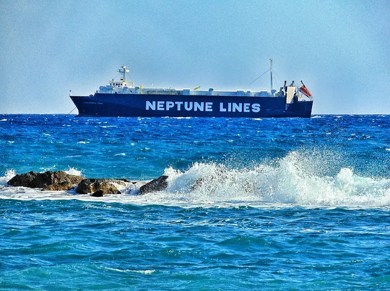 Грузовое судно Neptune Lines в море на фоне волн и прибрежных скал