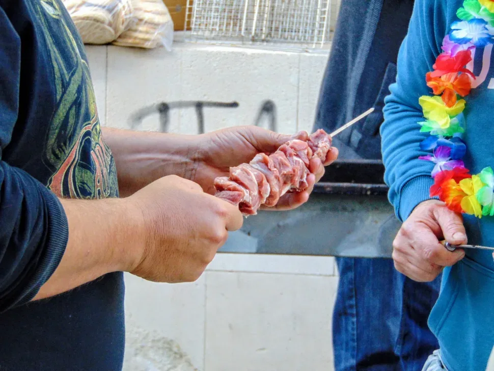 Кусок свежего мяса нанизывают на шампур перед жаркой