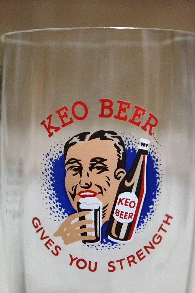 Крупный план принта на бокале KEO Beer с мужчиной, бутылкой и слоганом