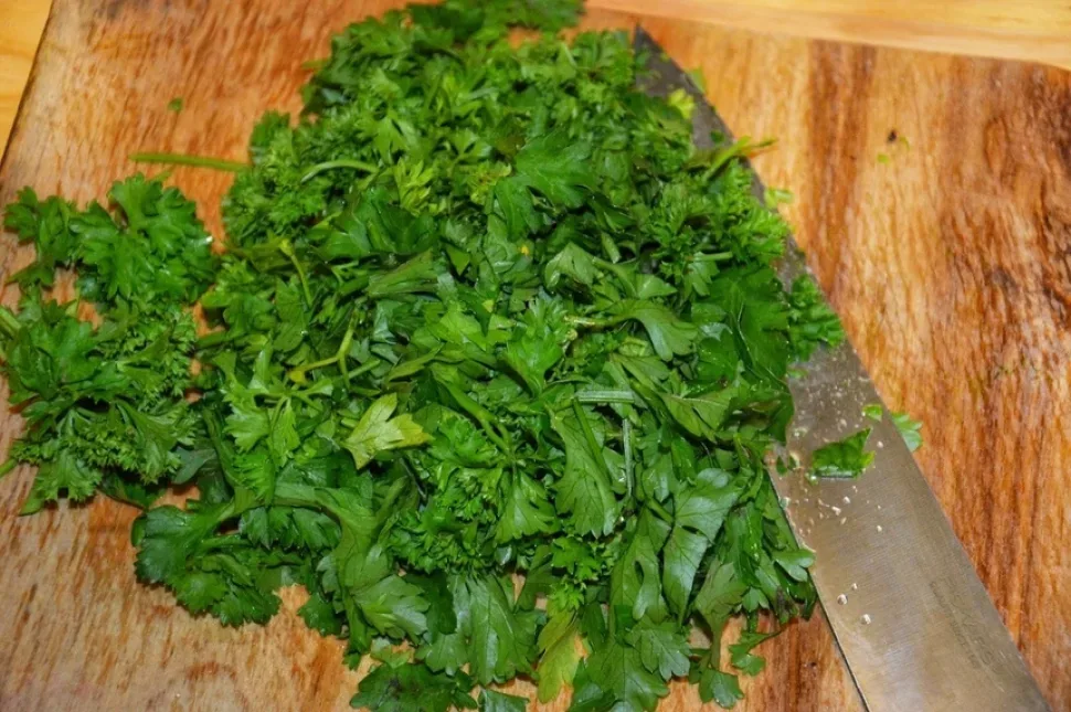 Нарезанный шпинат и зелень с кухонным ножом на доске Нарезанный шпинат и зелень с кухонным ножом на доске