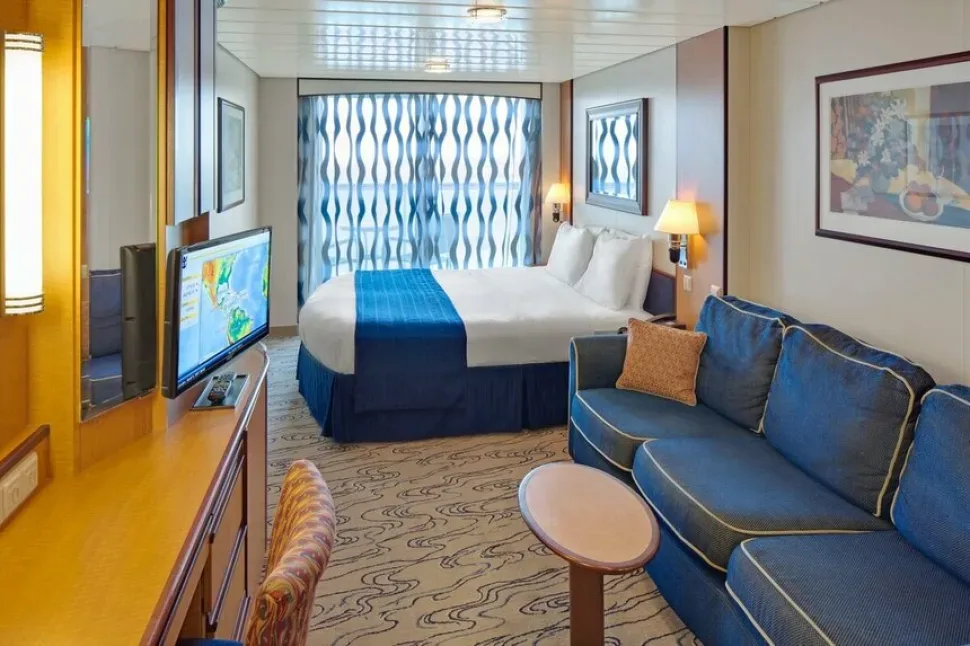 Комфортная каюта с балконом, кроватью и диваном на борту Jewel of the Seas