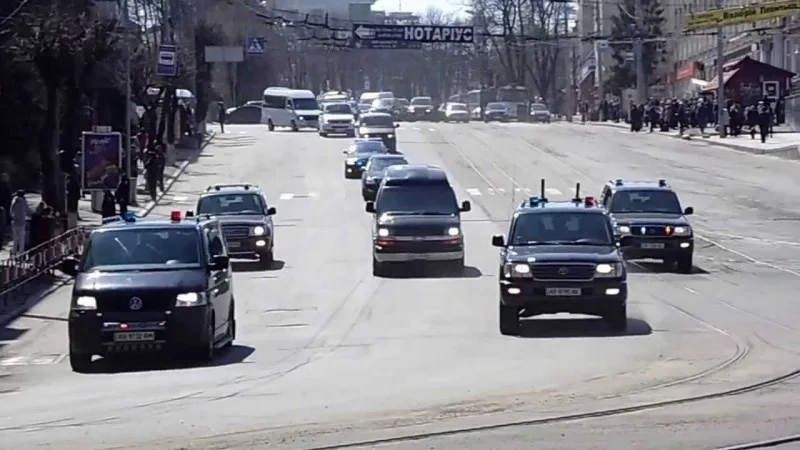 Колонна из нескольких автомобилей, предположительно президентский кортеж, едущий по городской улице