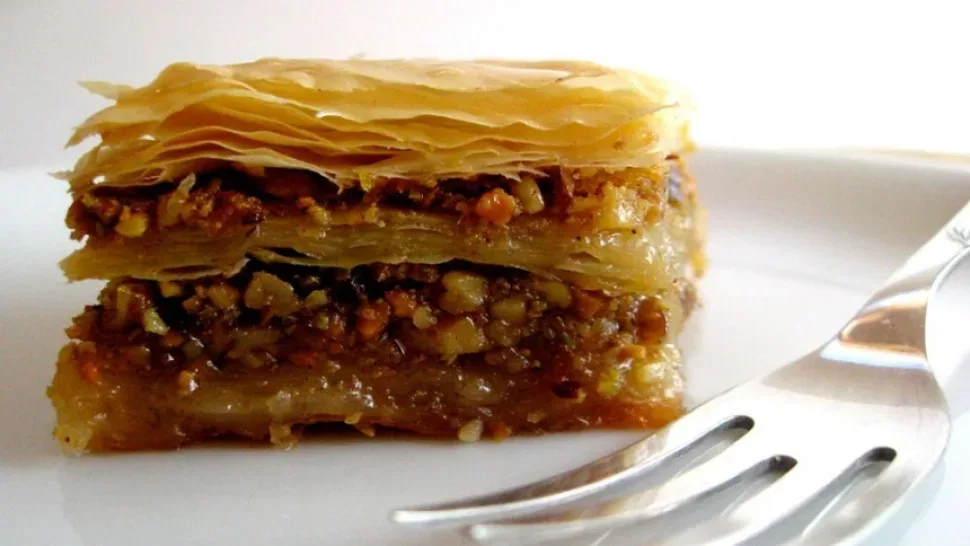 Кусочек пахлавы с ореховой начинкой и хрустящими слоями теста Кусочек пахлавы с ореховой начинкой и хрустящими слоями теста