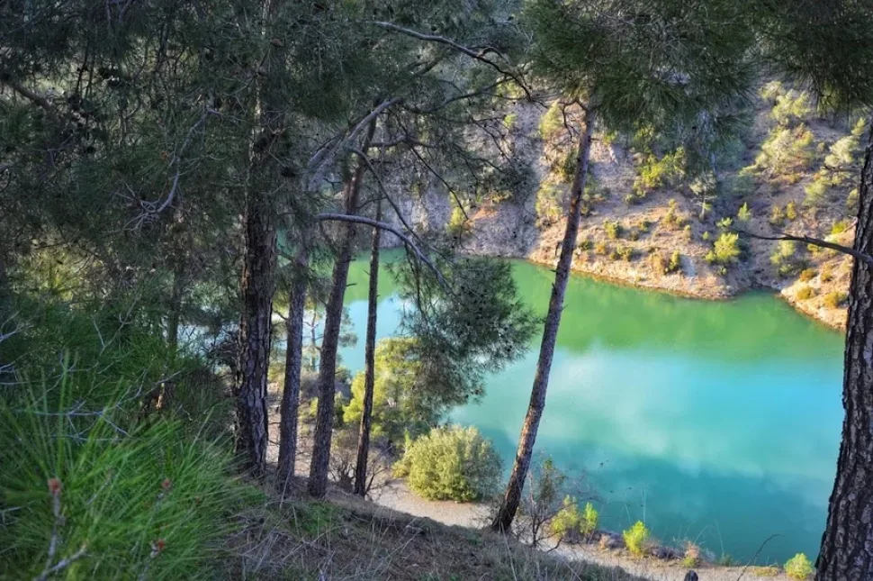 Изумрудная вода озера и покрытые соснами горы на горизонте
