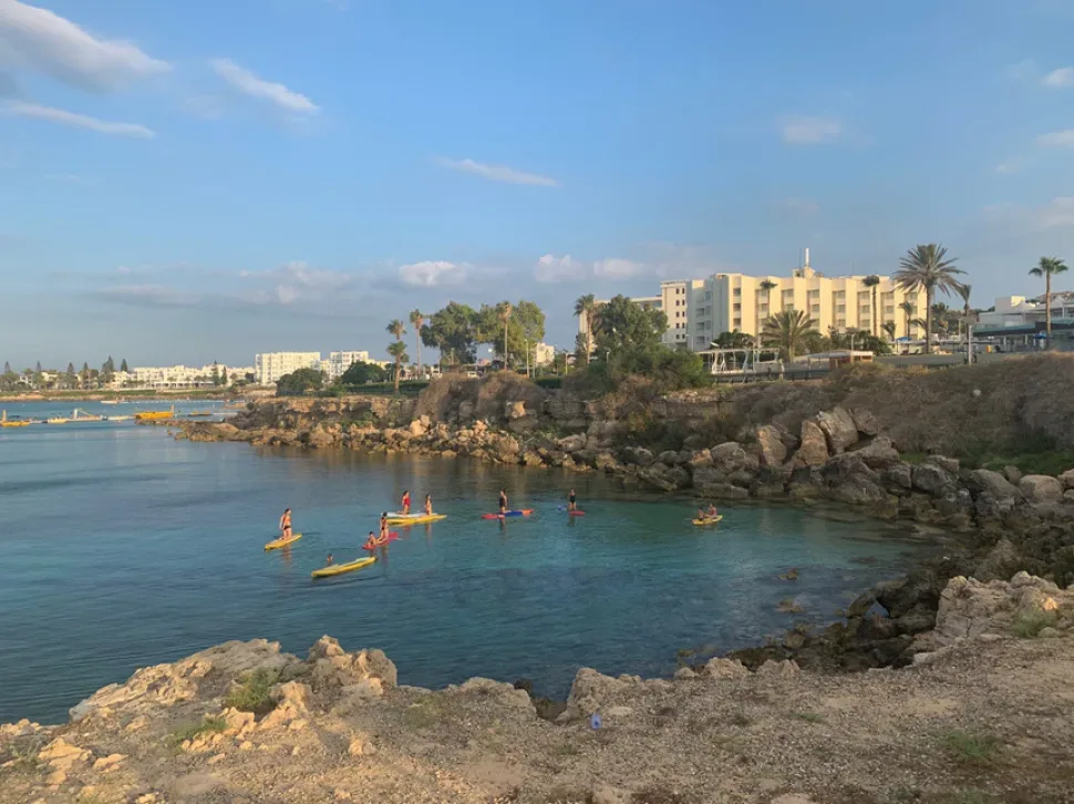 Три человека выполняют растяжку на SUP-досках в воде