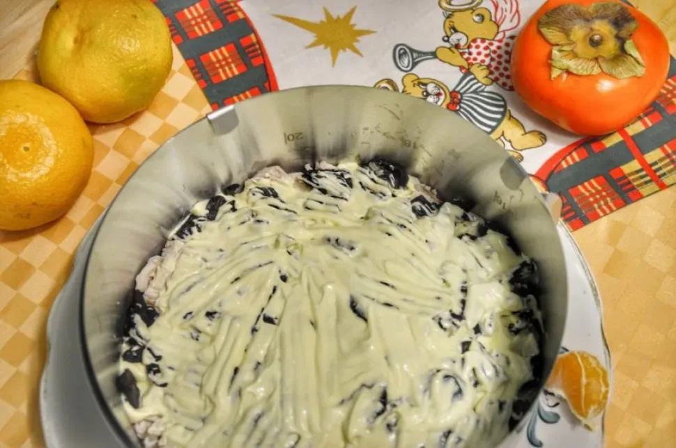 Чернослив, распределенный по слою курицы внутри формовочного кольца