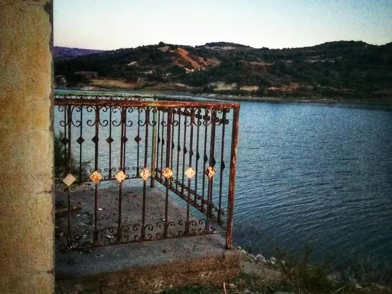 Ржавый кованый балкон дома над водой водохранилища Эврету