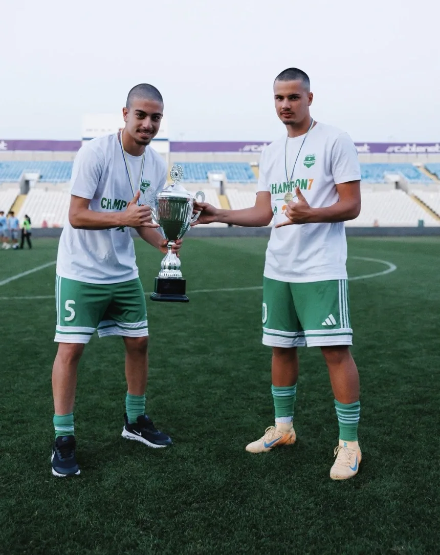 Два футболиста «Ариса» U17 держат чемпионский кубок и демонстрируют медали