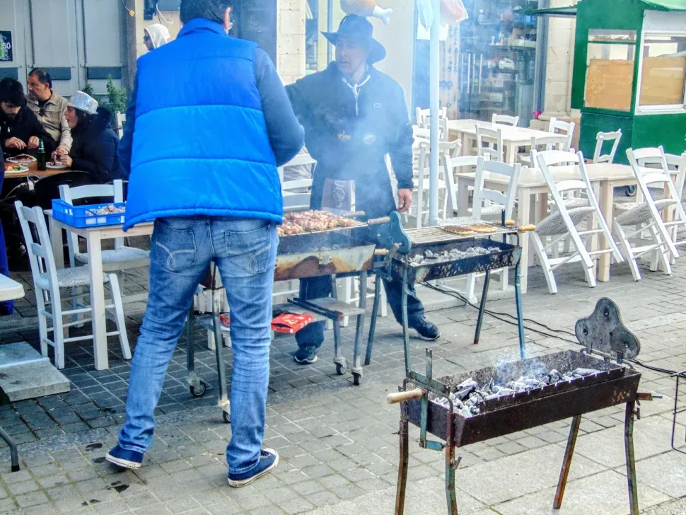 Два гриля и мужчины готовят мясо на открытой улице