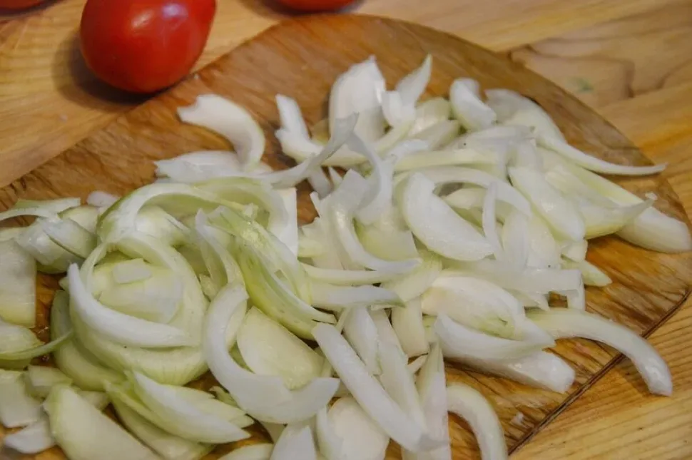 Лук репчатый нарезан ломтиками для выкладывания поверх мяса