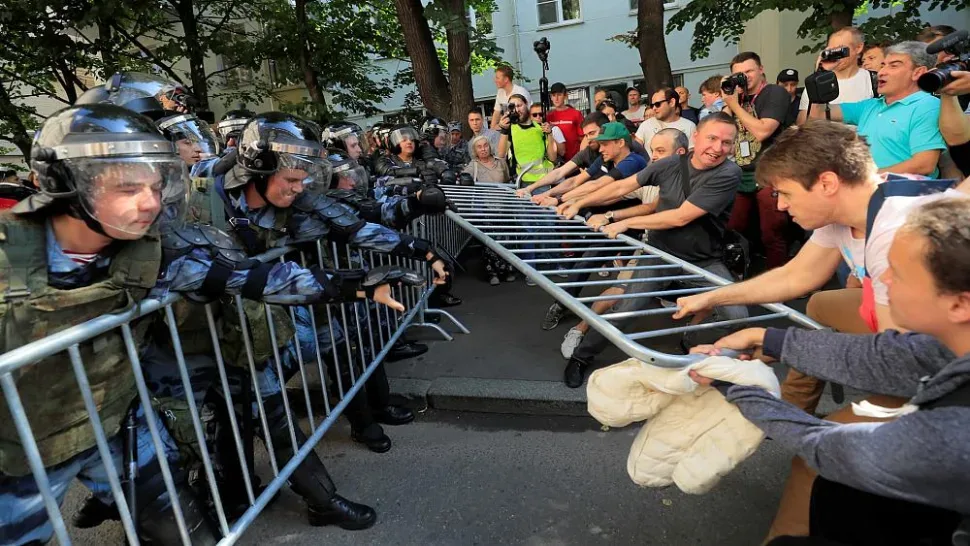 Противостояние полиции в шлемах и протестующих, тянущих металлические ограждения Противостояние полиции в шлемах и протестующих, тянущих металлические ограждения