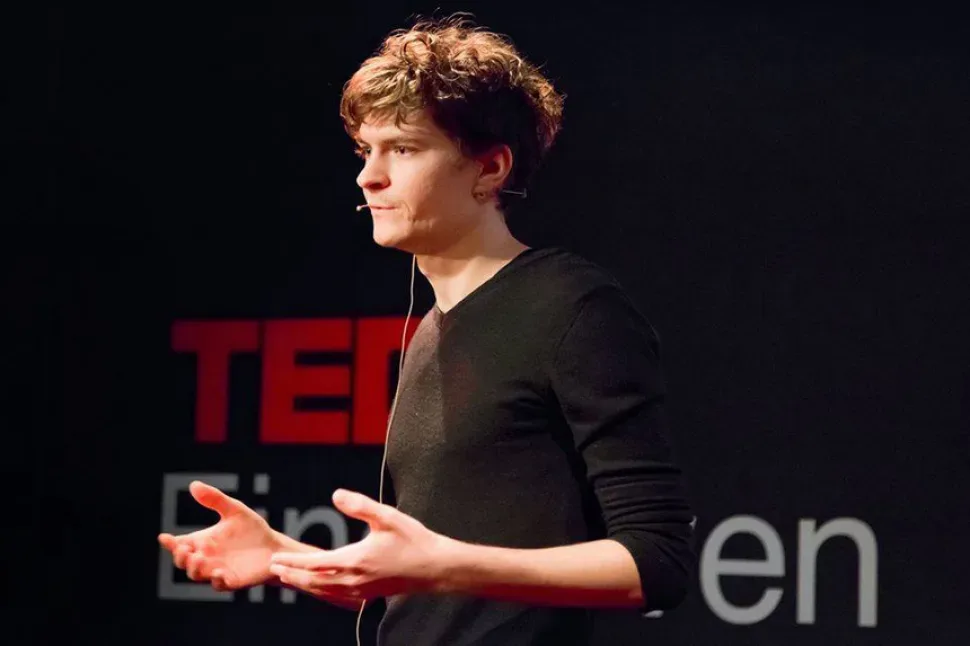 Докладчик на сцене TEDx во время выступления с петличным микрофоном
