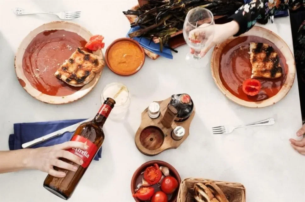 Вид сверху на тарелки тапас и наливающееся пиво Estrella Damm