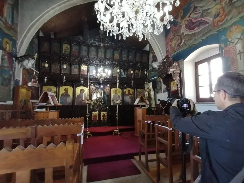 Флакон антисептика и церковные свечи на столике внутри храма