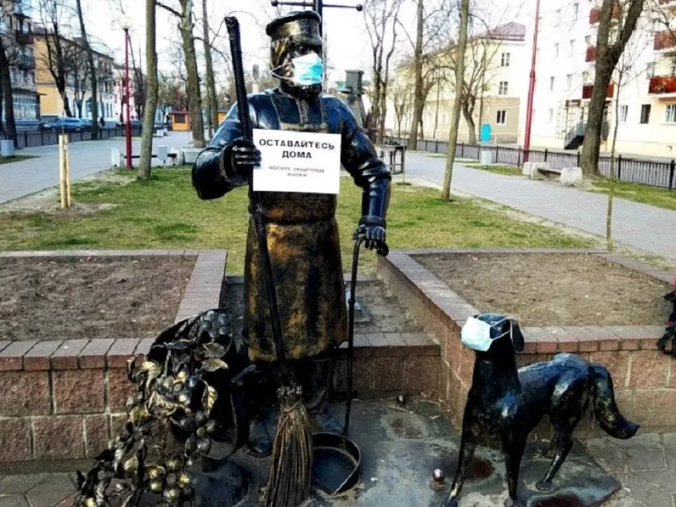Две уличные скульптуры в масках и антикоронавирусные плакаты