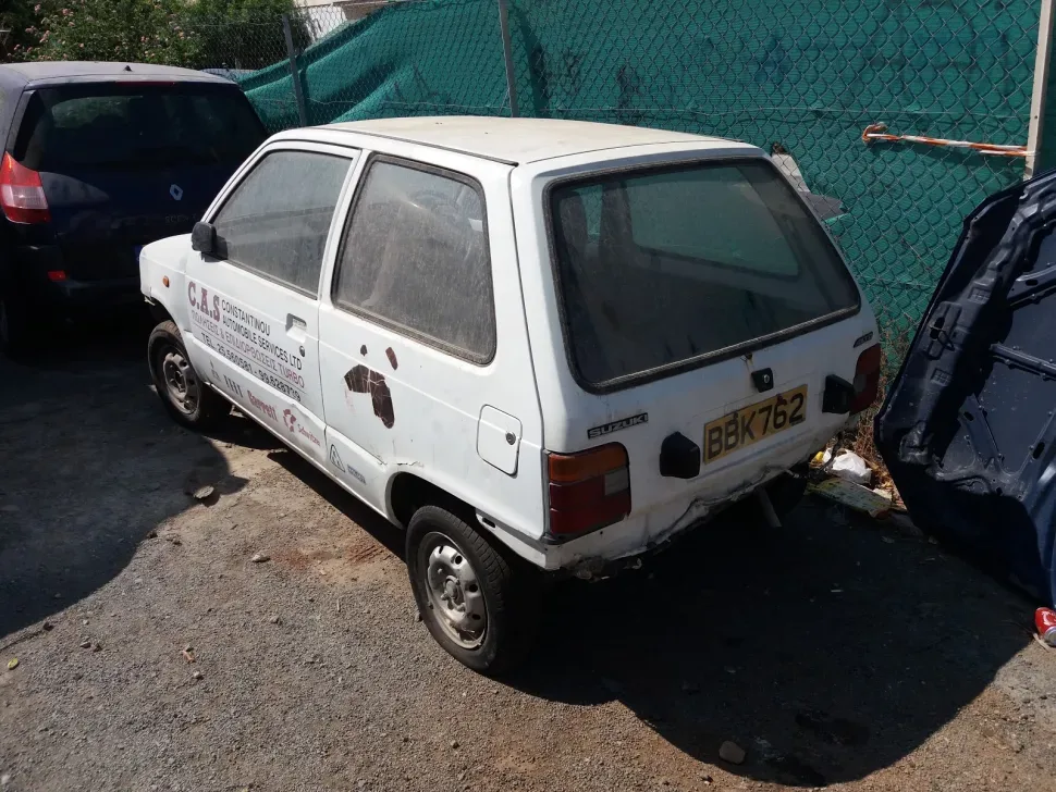 Пыльная и повреждённая маленькая городская машина Mazda 323