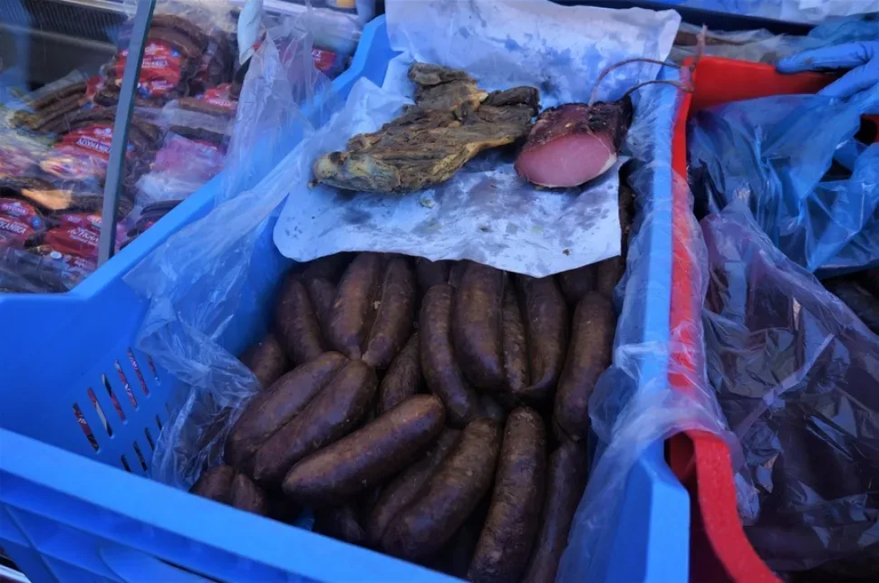 Крупные домашние колбасы в ящике на прилавке мясного продавца