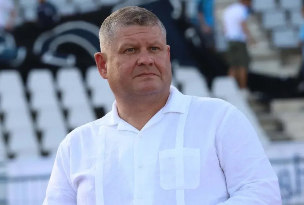 Мужчина в белой рубашке на фоне пустых трибун стадиона