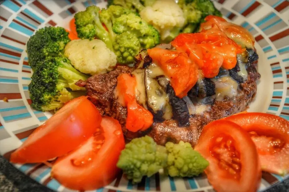 Отбивная с брокколи, цветной капустой и мини-морковью на белой тарелке