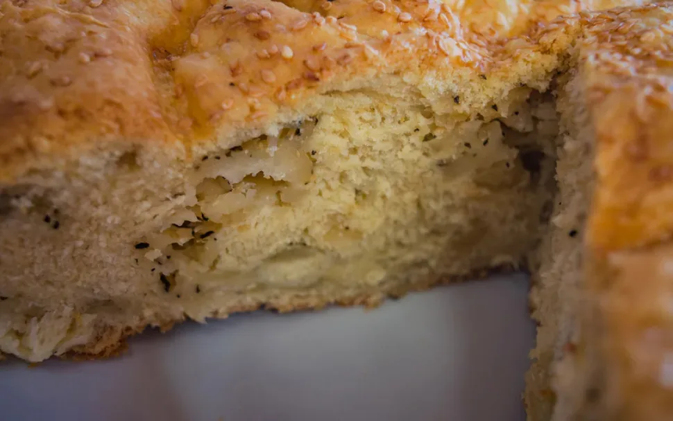 Кусок Халумопиты с золотистой корочкой и семенами кунжута на тарелке