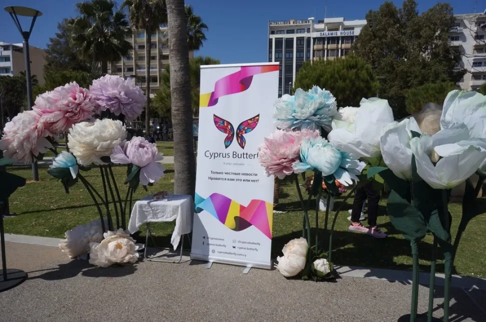 Три участника акции позируют у баннера Cyprus Butterfly с розами