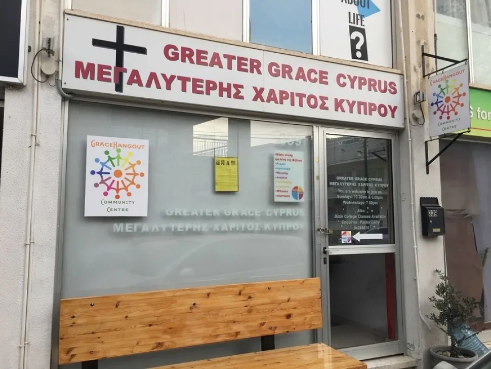 Фасад с вывеской Greater Grace Cyprus и надписью на греческом языке