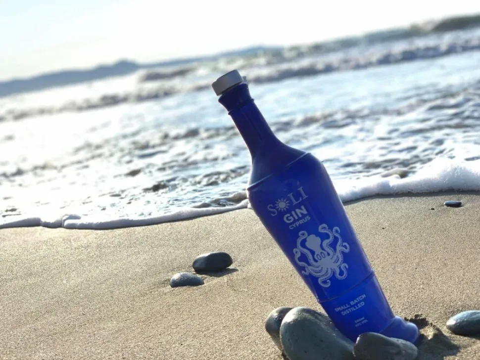 Бирюзовая бутылка Soli London Dry Gin на песчаном пляже у моря