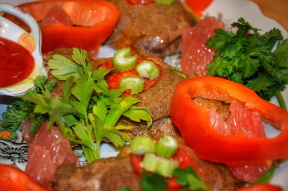 Противень с рядами куриных кусков, покрытых маринадом и томатом