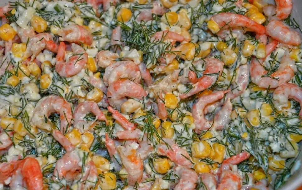 Добавленные очищенные креветки поверх заправленной кукурузой и укропом