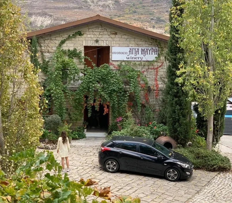 Вход в винодельню с вывеской winery, припаркованный автомобиль и человек у фасада