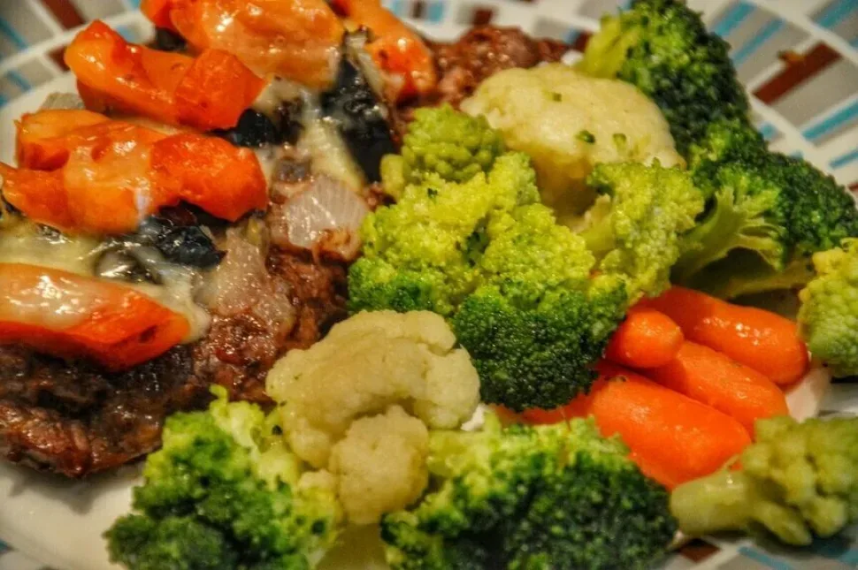 Порция отбивной с курагой и брокколи на тарелке