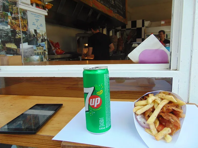 Уличный гирос с банкой 7up и порцией картофеля фри у окна раздачи