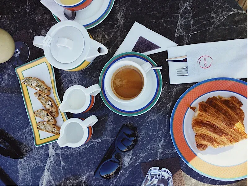 Круассан и сервировка с чашкой кофе в Colors cafe при отеле Four Seasons в Лимассоле Круассан и сервировка с чашкой кофе в Colors cafe при отеле Four Seasons в Лимассоле