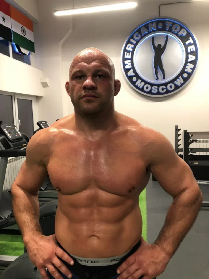 Спортсмен в зале с голым торсом на фоне логотипа American Top Team Moscow Спортсмен в зале с голым торсом на фоне логотипа American Top Team Moscow