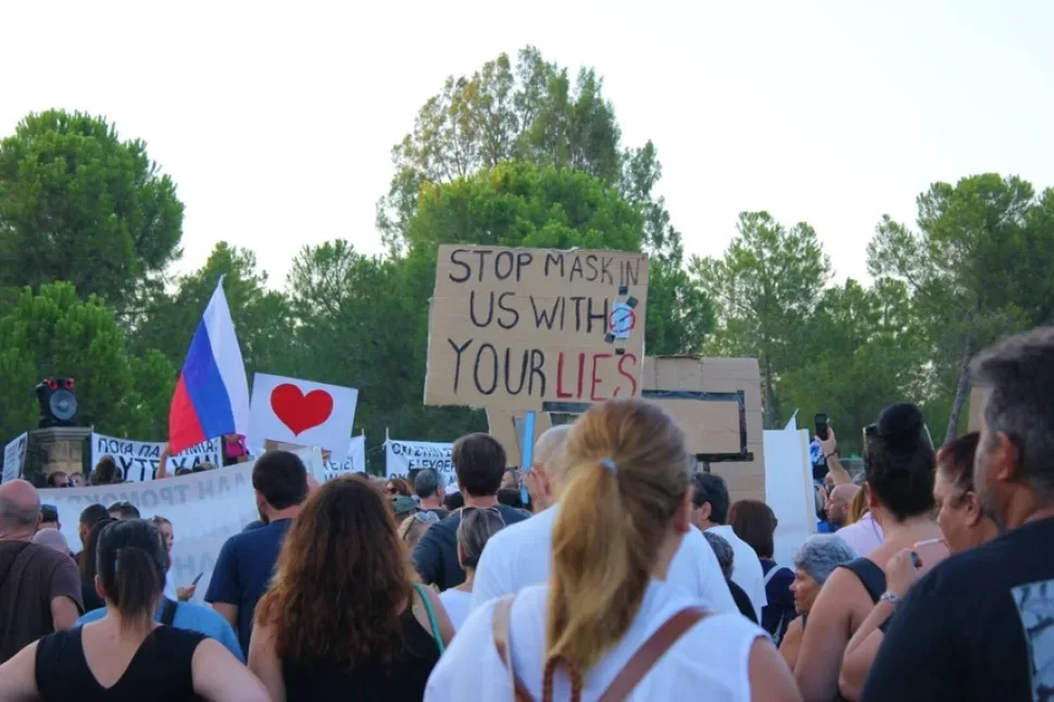 Протестующие стоят на дороге с плакатами «My body my choice» и «Masks make us slaves