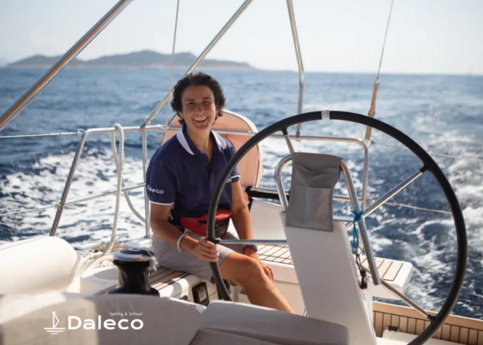 Человек в футболке с логотипом Daleco за штурвалом учебной яхты в море Человек в футболке с логотипом Daleco за штурвалом учебной яхты в море