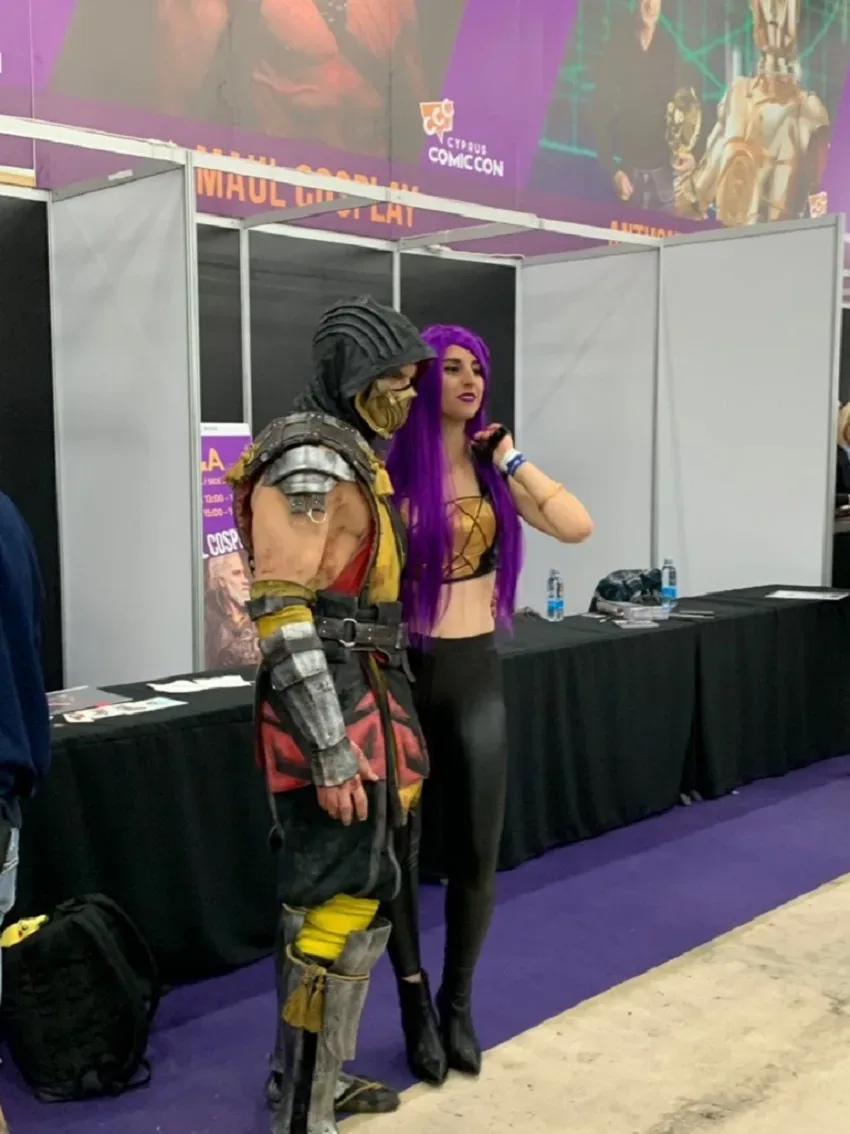 Косплееры у стенда с баннерами Cyprus Comic Con внутри павильона