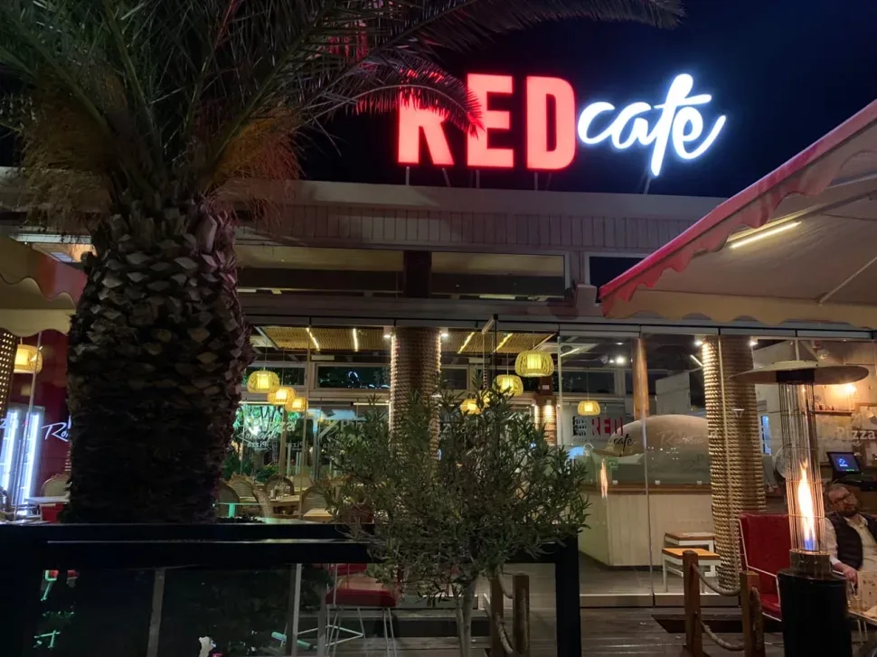 Неоновая вывеска RED cafe над фасадом заведения на Молос