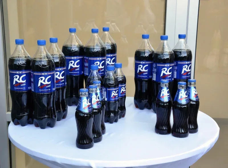 Ассортимент бутылок RC Cola разных объёмов на белом столе