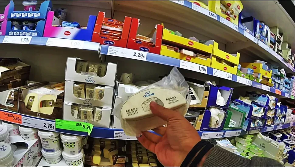 Рука покупателя берет упаковку молочного продукта с полки супермаркета