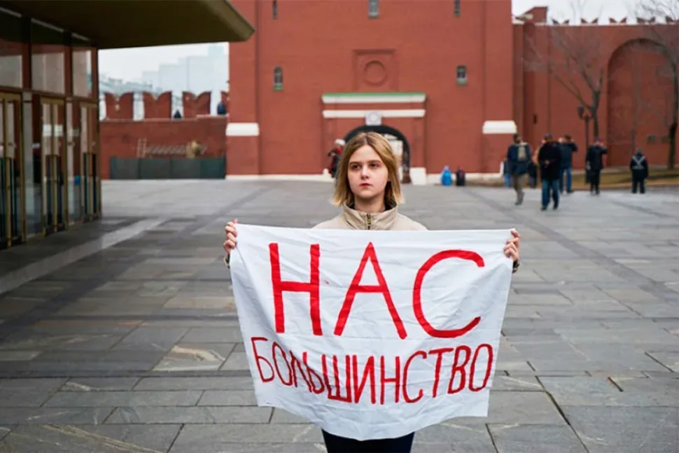 Девушка с плакатом «НАС БОЛЬШИНСТВО» на городской площади